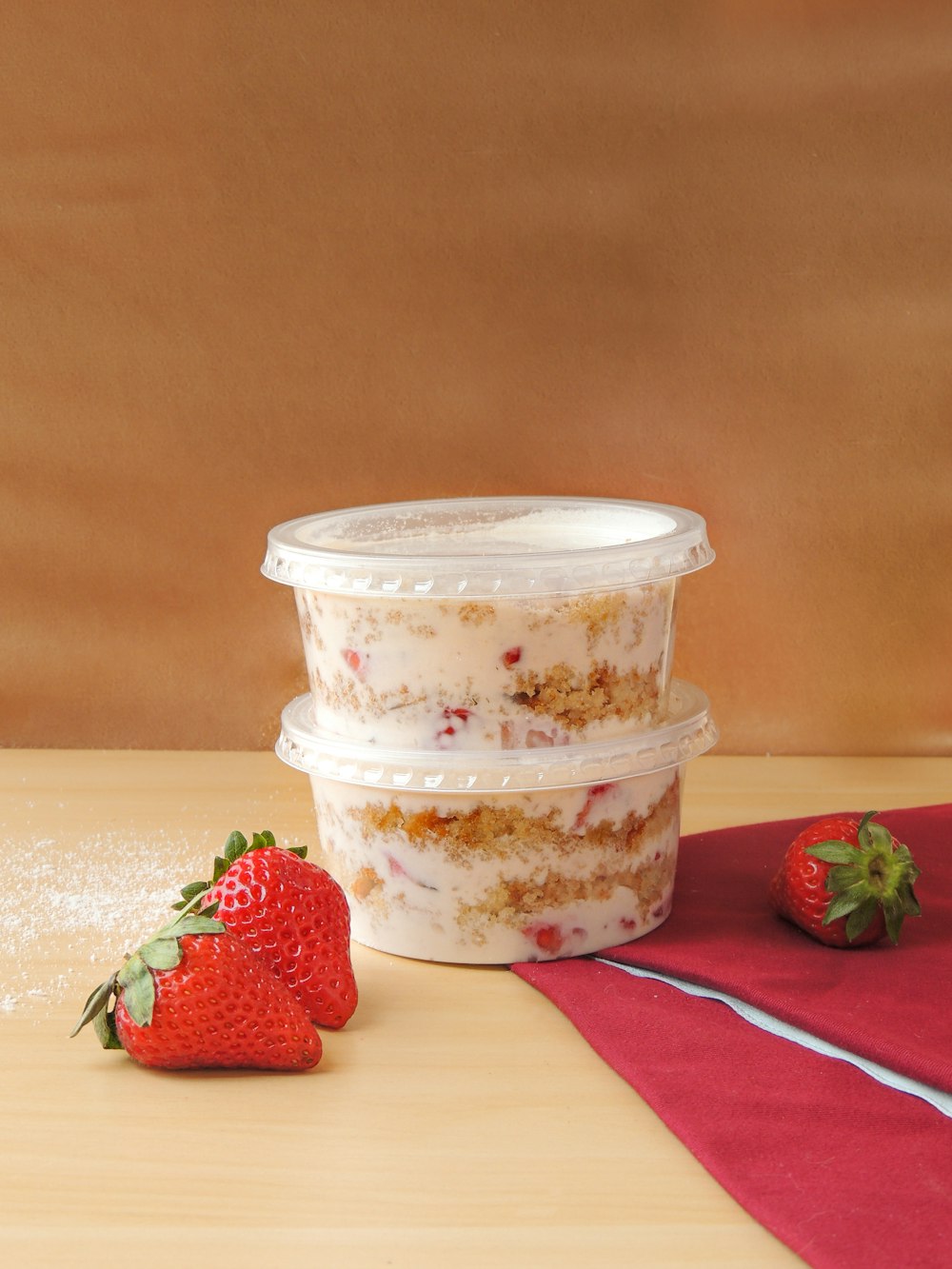 three plastic containers with strawberries on a table