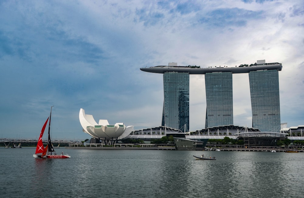 a sailboat on a body of water in front of some tall buildings