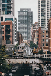 a train traveling over a bridge next to tall buildings