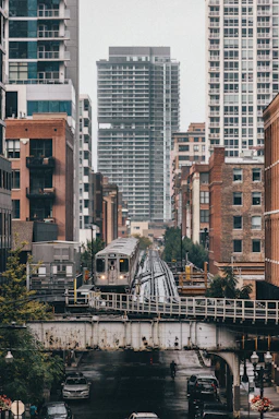 a train traveling over a bridge next to tall buildings