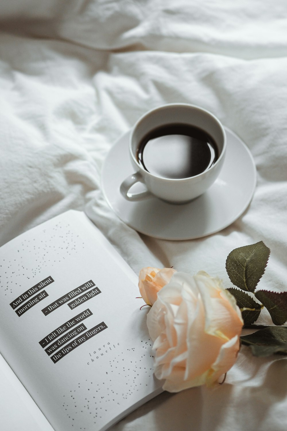 a cup of coffee and a book on a bed