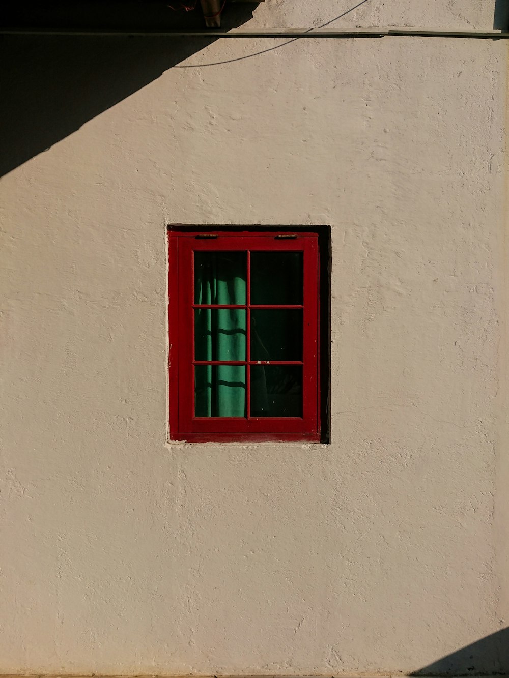 a white building with a red window and a green curtain