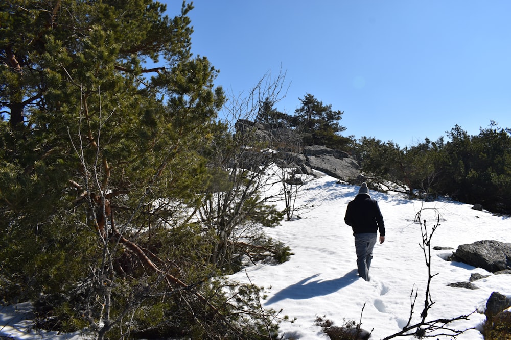 a man walking up a snow covered hill