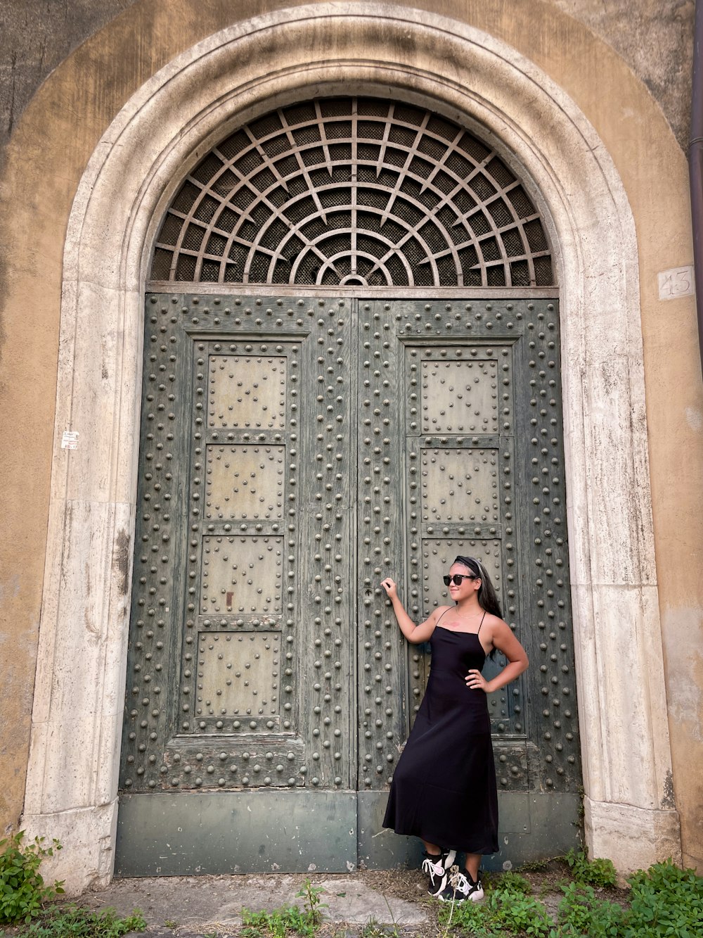 uma mulher em um vestido preto em pé na frente de uma porta