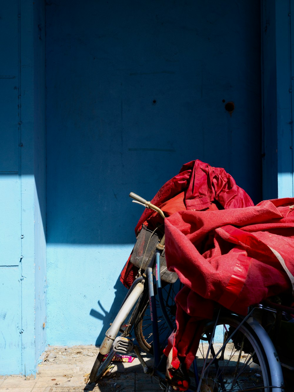 a bicycle with a red blanket on it parked in front of a blue building