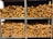 Several stacks of neatly chopped firewood are arranged on metal shelves. The wood pieces have a natural, rustic appearance with varying shades of brown and some visible bark. The shelves are organized in a neat and orderly fashion.