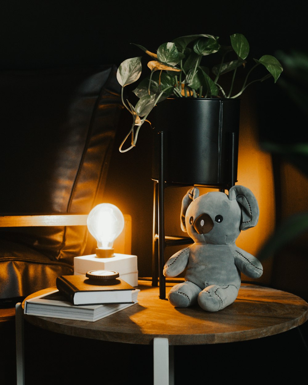 a stuffed elephant sitting on a table next to a lamp
