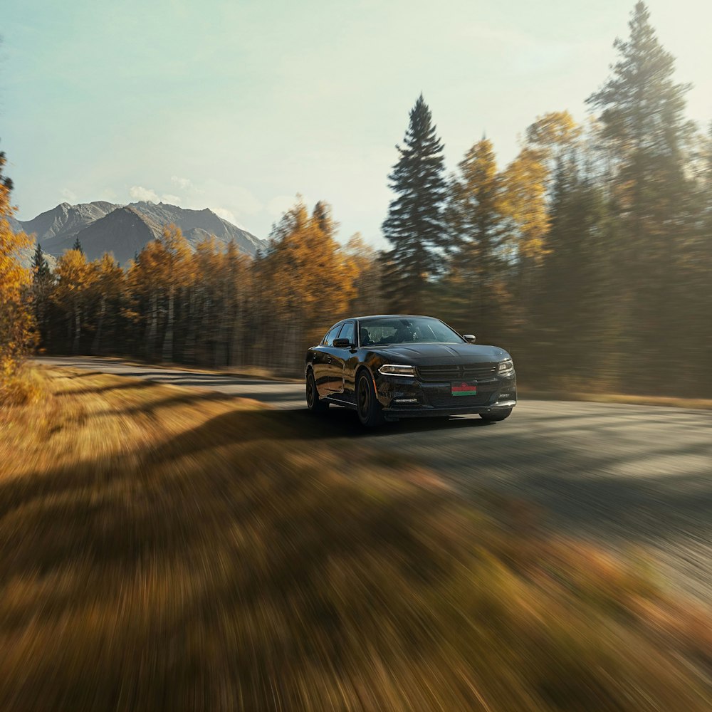 a black car driving down a country road