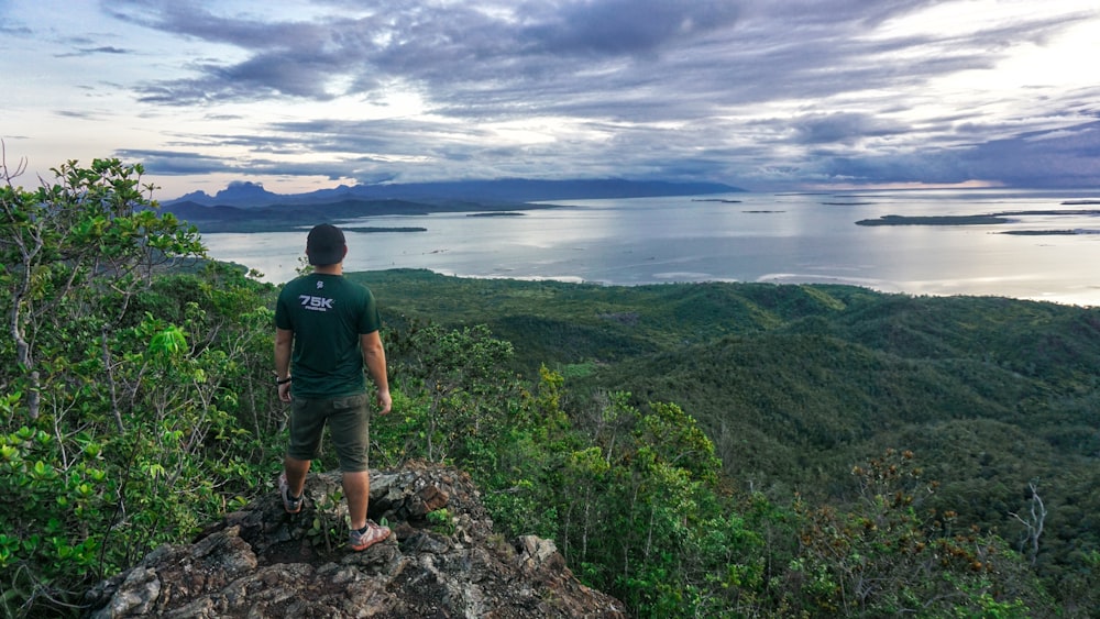 a man standing on top of a lush green hillside