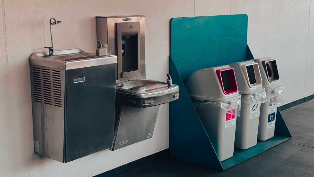 a row of trash cans next to a water dispenser