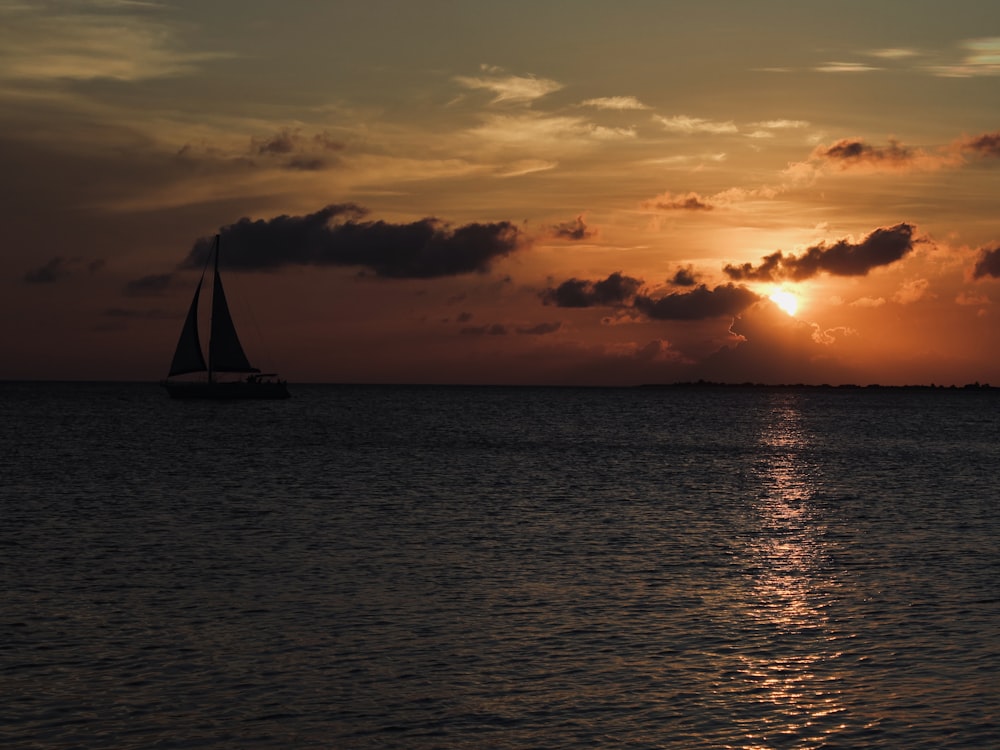 a sailboat in the ocean at sunset