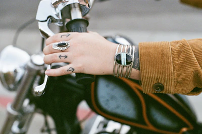 Hand wearing a thick leather biker bracelet resting on a motorcycle handlebar.