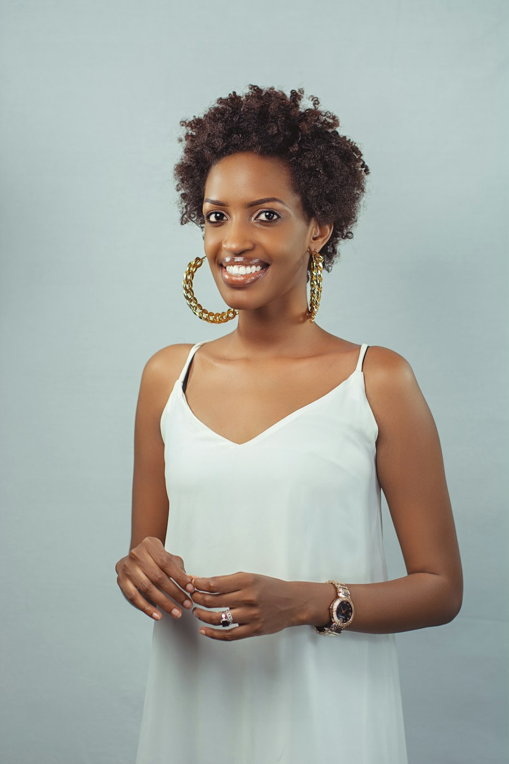 a woman wearing a white dress and gold hoop earrings