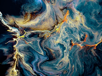 A fluid art composition featuring vibrant swirling patterns with shades of deep blue, bright orange, and hints of gold and white. The dynamic flow suggests aquatic or cosmic movement, with striking lines and curves creating a vivid contrast against the darker background.