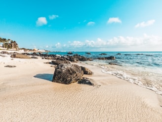a sandy beach and shore line with rocks