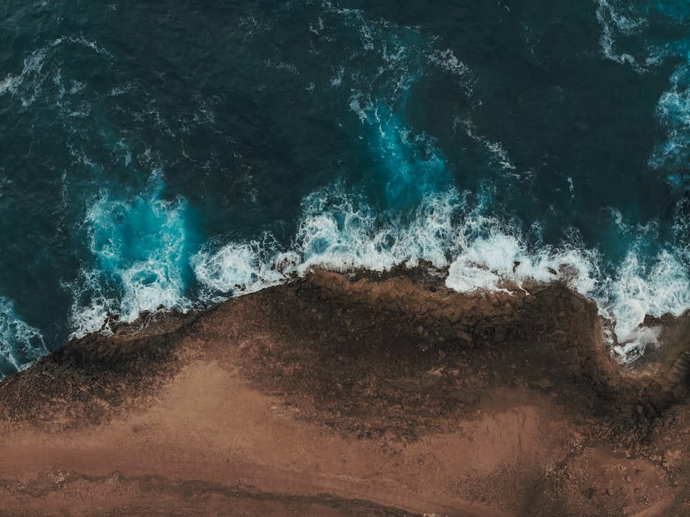 an aerial view of the ocean with waves crashing on the shore