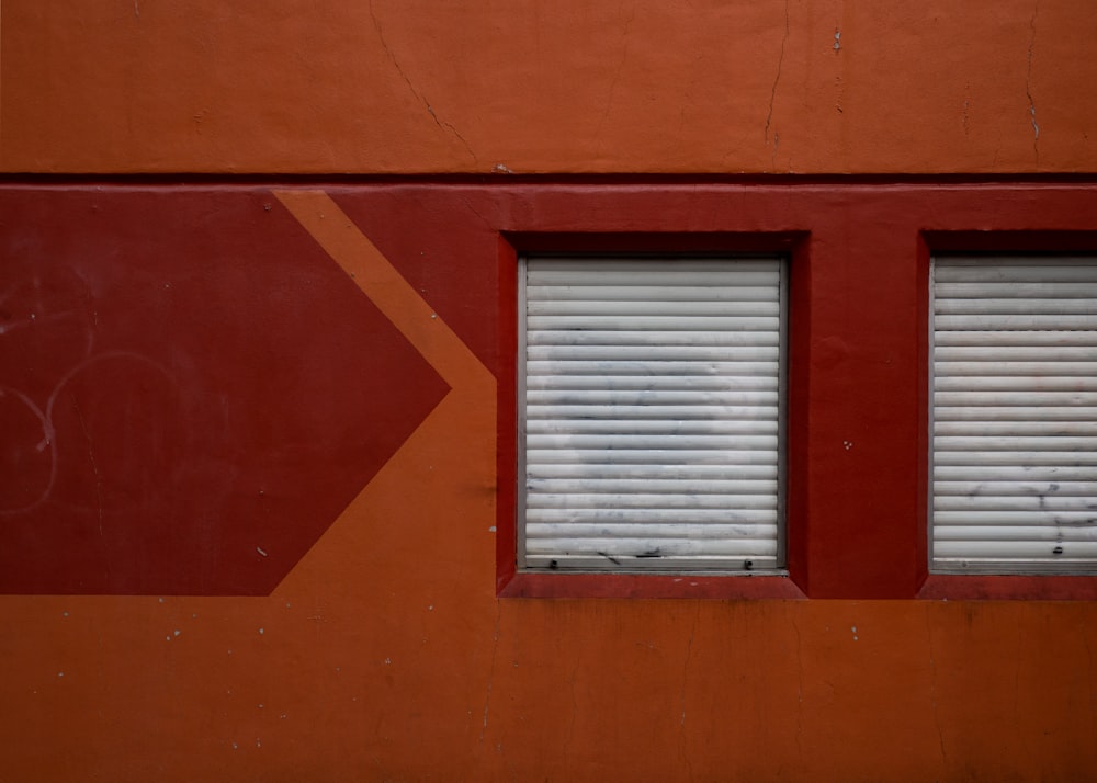 a red wall with two windows and an arrow painted on it
