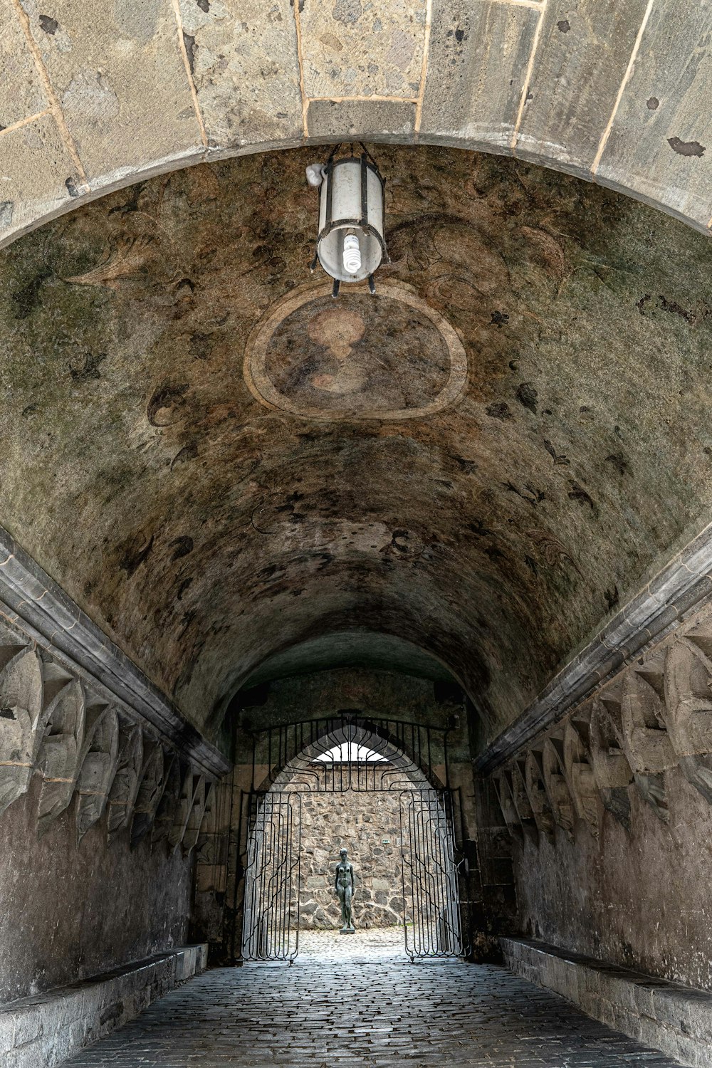 a stone tunnel with a light hanging from the ceiling