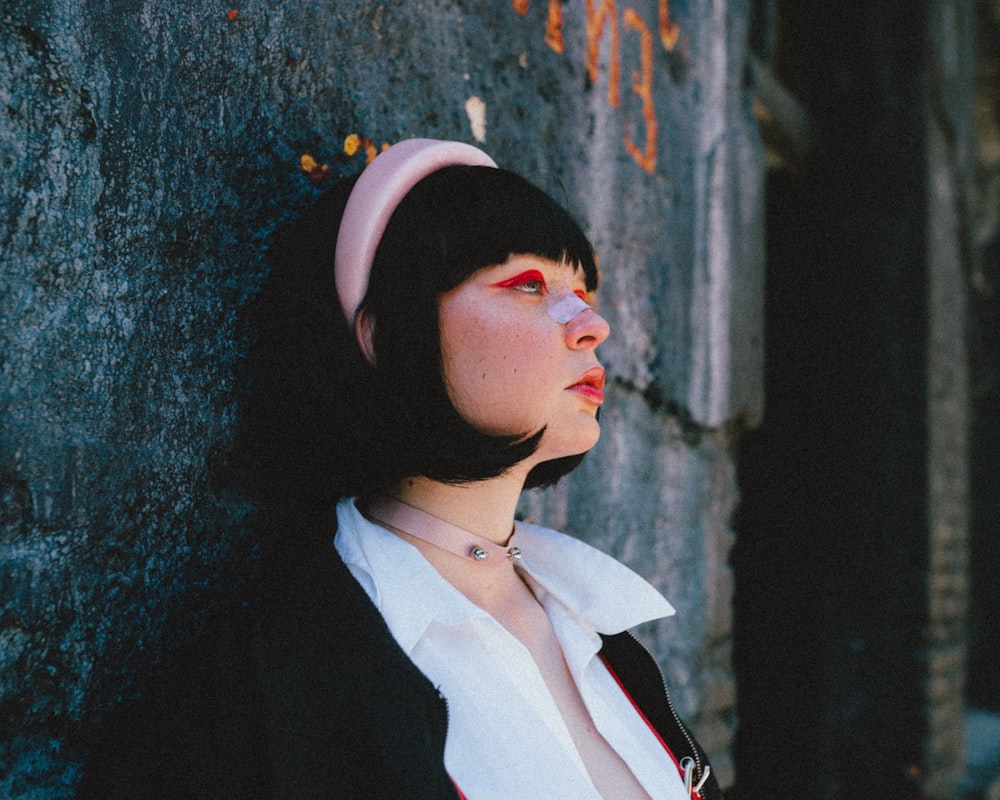 a woman leaning against a wall with a cigarette in her mouth