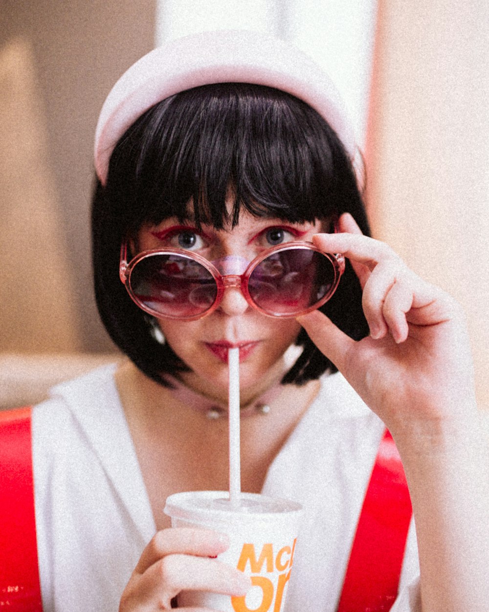 a woman wearing sunglasses and a hat drinking a drink