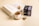 An open book with a dry leaf resting on its pages sits alongside a white cup of tea placed on a coaster. A box of tea with the label 'Pietra di Luna' and a teabag are nearby, creating a cozy and relaxing atmosphere.