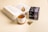 An open book with a dry leaf resting on its pages sits alongside a white cup of tea placed on a coaster. A box of tea with the label 'Pietra di Luna' and a teabag are nearby, creating a cozy and relaxing atmosphere.