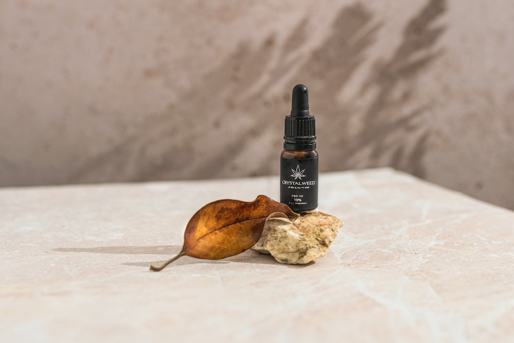 a close up of a bottle of essential oils next to a leaf