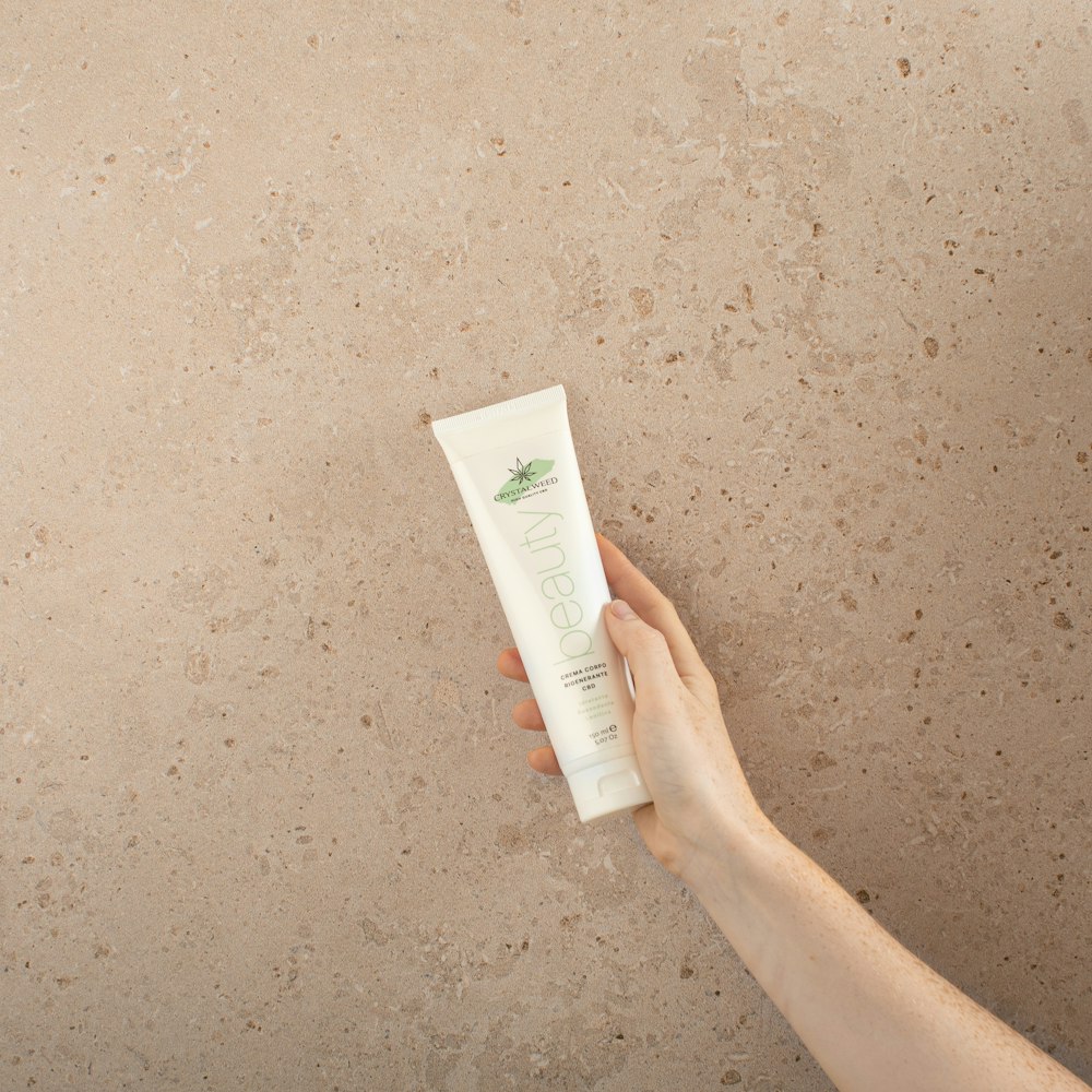 a person holding a tube of hand cream