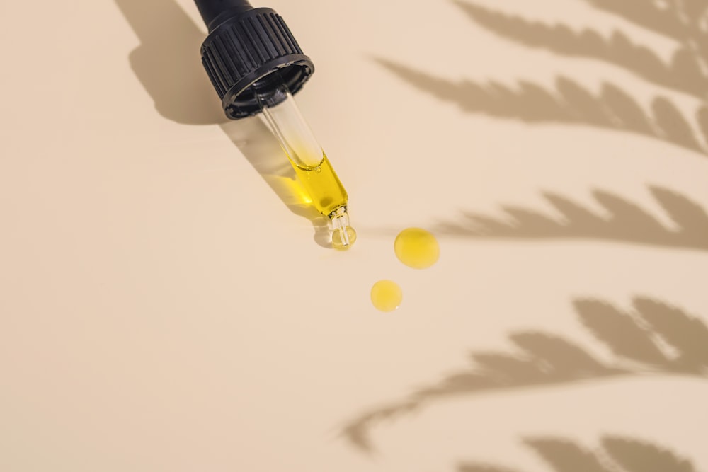 a dropper bottle filled with yellow liquid sitting on top of a table