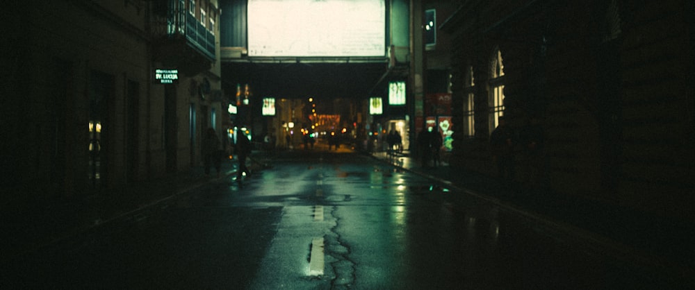 a city street at night with people walking on the sidewalk