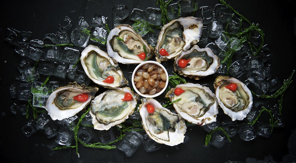 a plate of oysters on ice with a cherry in a bowl