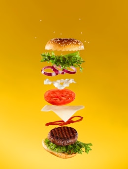 a hamburger flying through the air with a lot of toppings on it