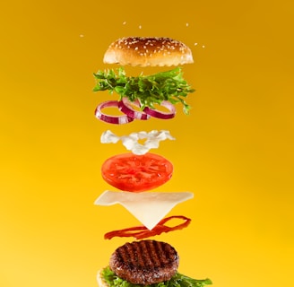 a hamburger flying through the air with a lot of toppings on it