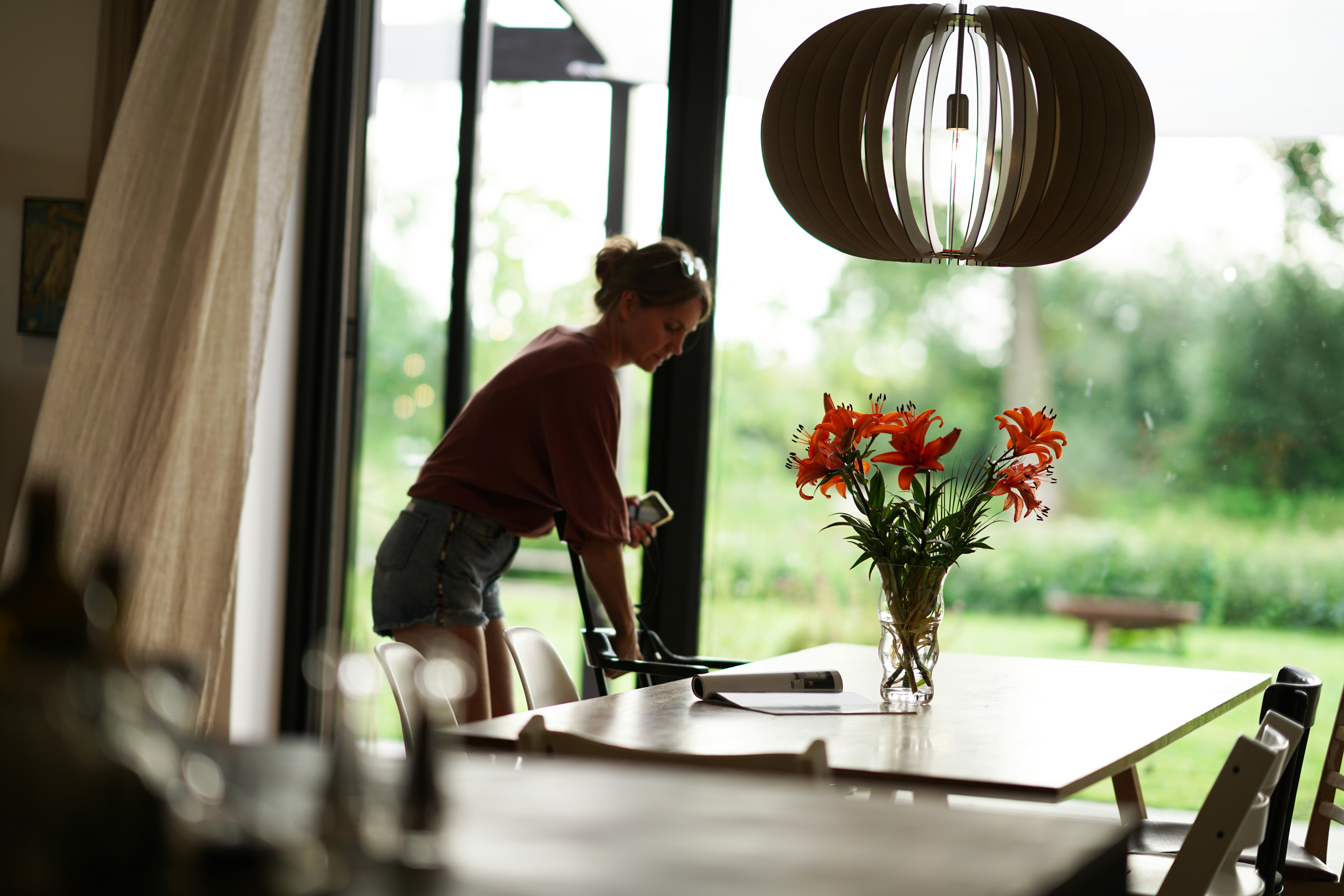 a woman sitting at a table with a vase of flowers