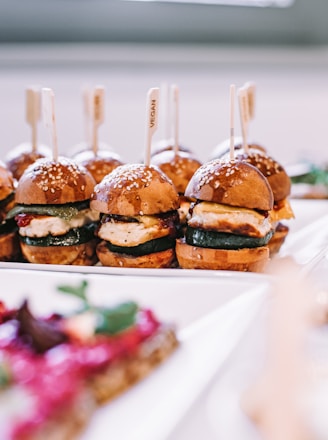 a row of mini sandwiches sitting on top of a white plate