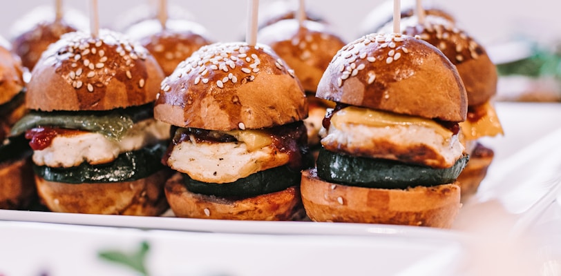 a row of mini sandwiches sitting on top of a white plate