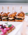 a row of mini sandwiches sitting on top of a white plate