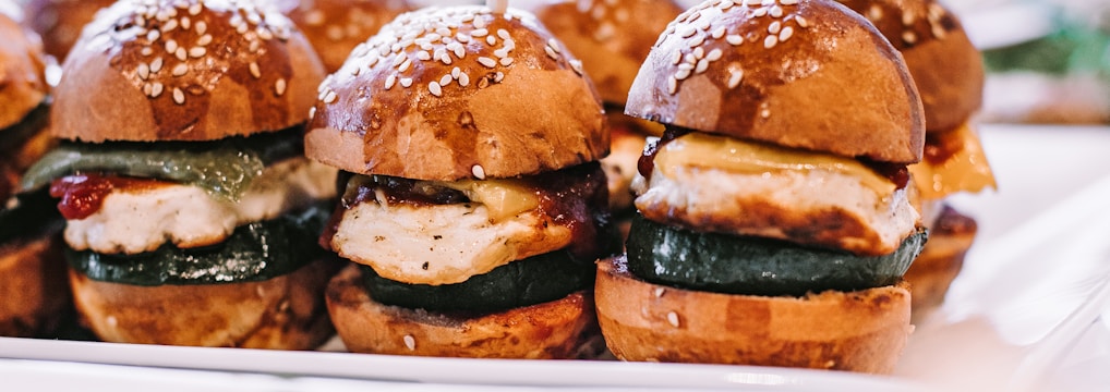 a row of mini sandwiches sitting on top of a white plate