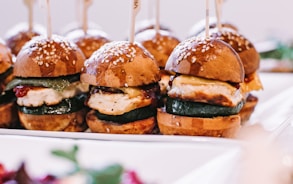 a row of mini sandwiches sitting on top of a white plate