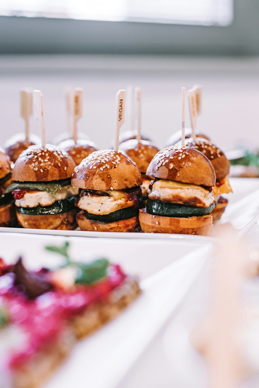 Una fila de mini sándwiches sentados encima de un plato blanco