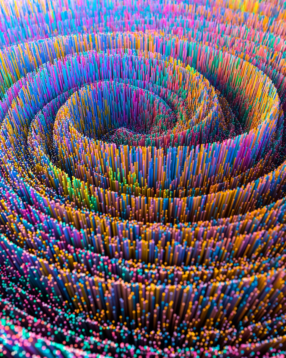 a large group of colored pencils are arranged in a spiral