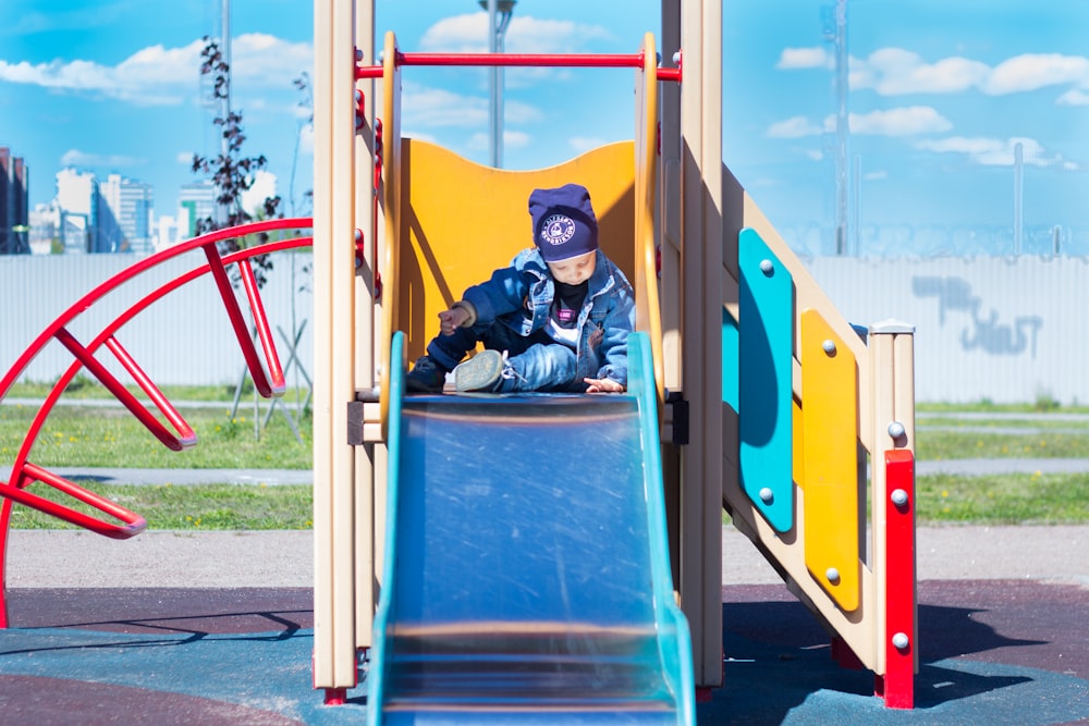 a boy sitting on a slide at a playground
