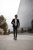A stylish man in a tailored suit walking confidently down a city street, embodying modern sophistication.