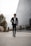 A stylishly dressed man walking confidently in a modern urban setting.