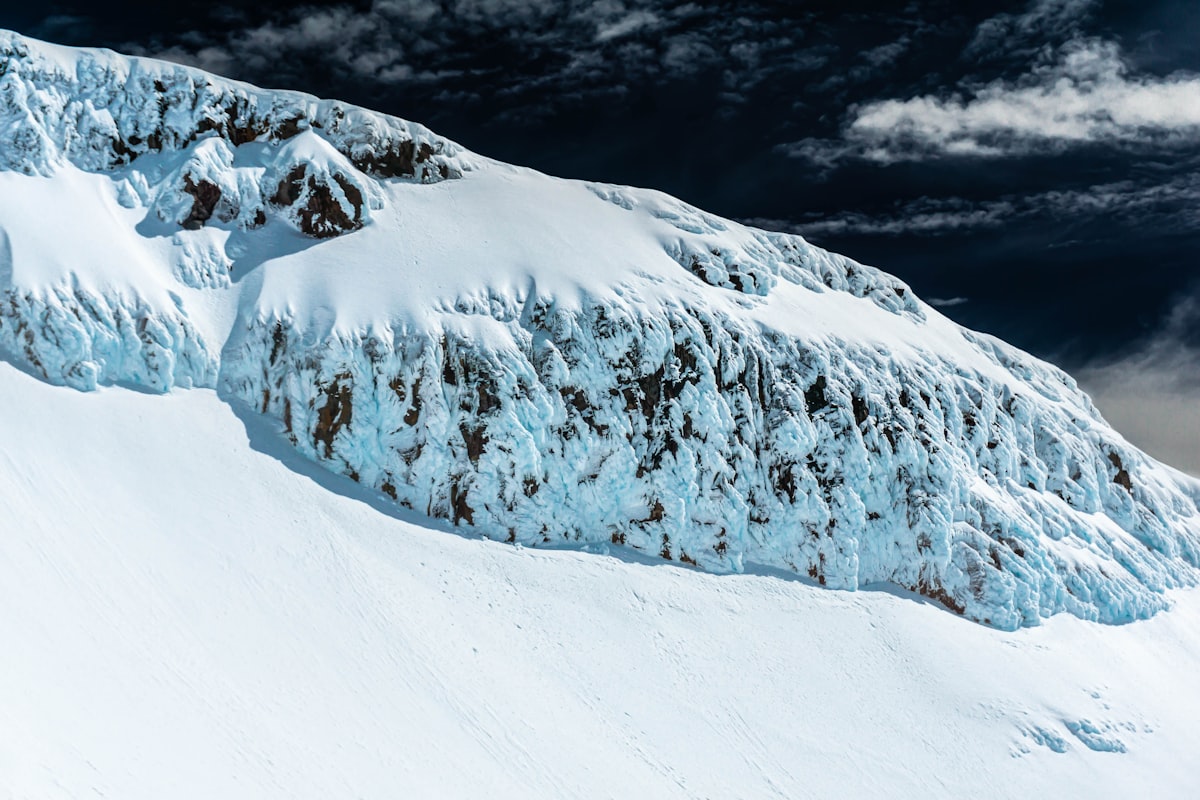 Skier descending snow-covered alpine slope, backcountry skiing