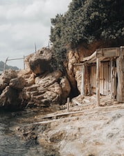 a wooden shack sitting on top of a cliff next to a body of water