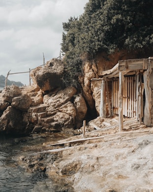 a wooden shack sitting on top of a cliff next to a body of water