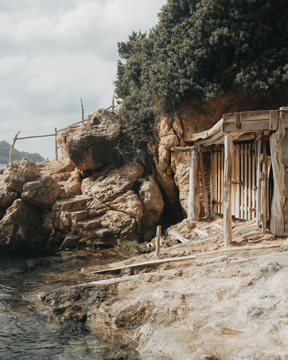 a wooden shack sitting on top of a cliff next to a body of water