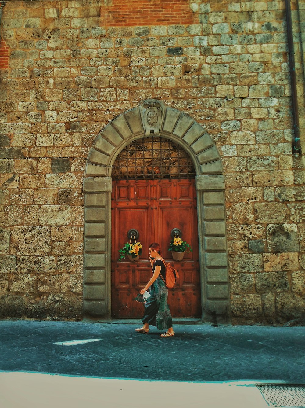 a woman walking down a street past a red door