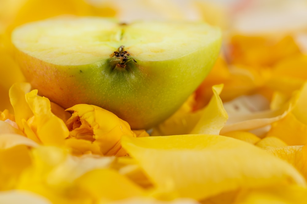 a green apple sitting on top of a pile of yellow flowers